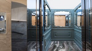 Ein Badezimmer mit verzierten Metalltüren und einem Marmorboden.