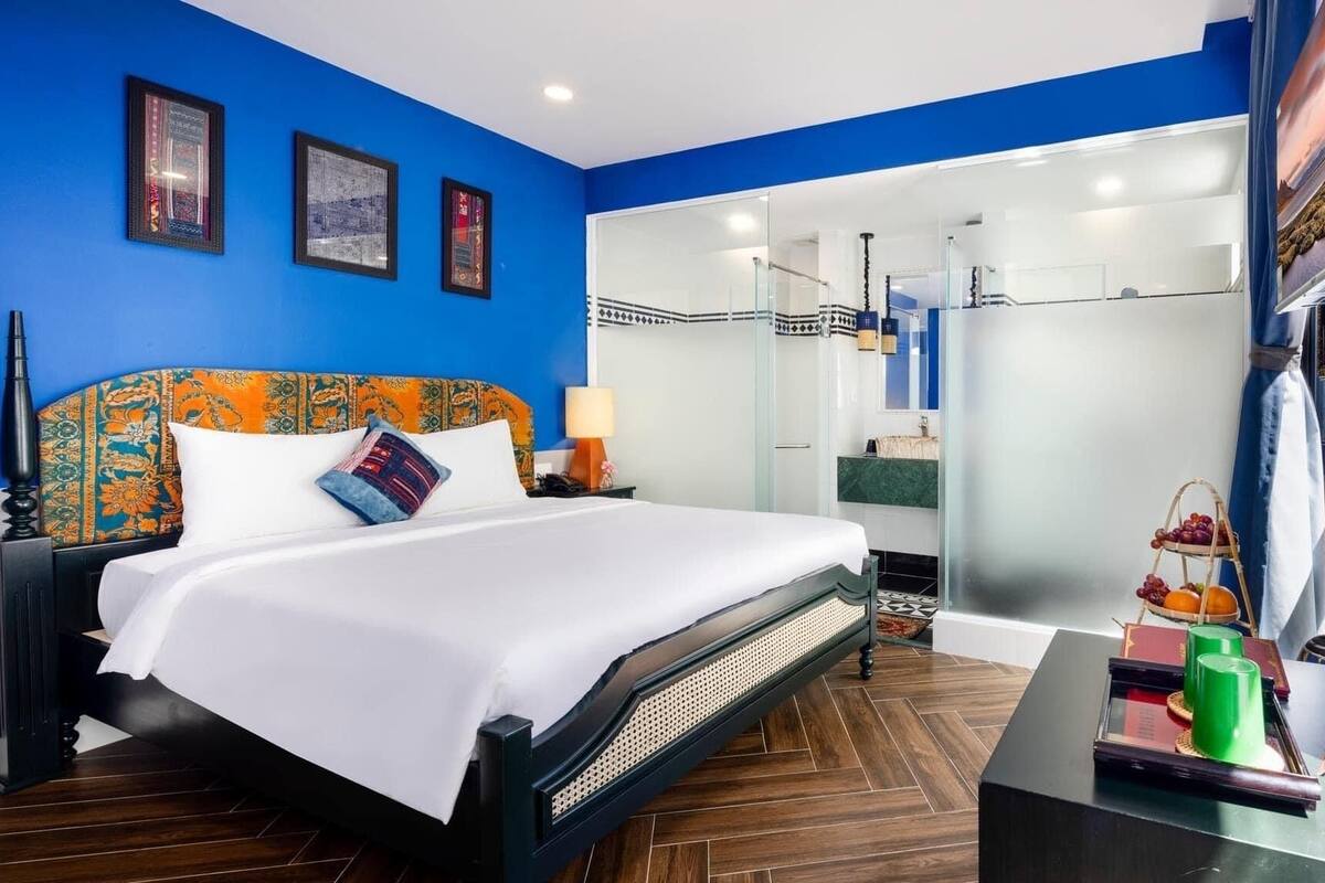 Una habitación de hotel moderna con una cama grande, cabina de ducha de vidrio y vistas a la ciudad.