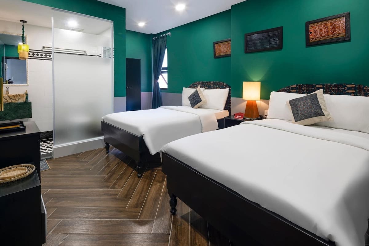 Habitación de hotel con dos camas, un escritorio, una lámpara y un espejo.