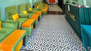 Un hall d’hôtel avec des canapés verts, un comptoir d’accueil et un sol à motifs.