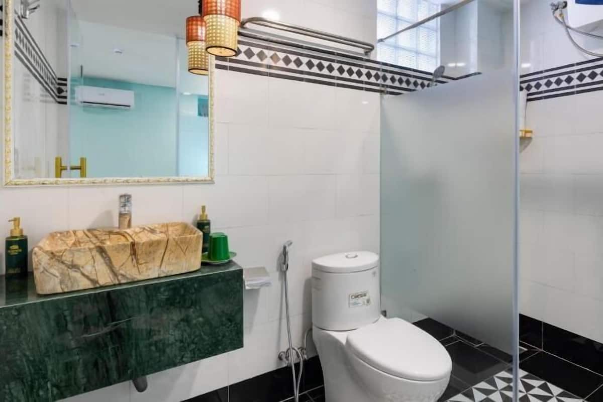 Un baño con lavamanos de mármol, inodoro y cabina de ducha de vidrio.
