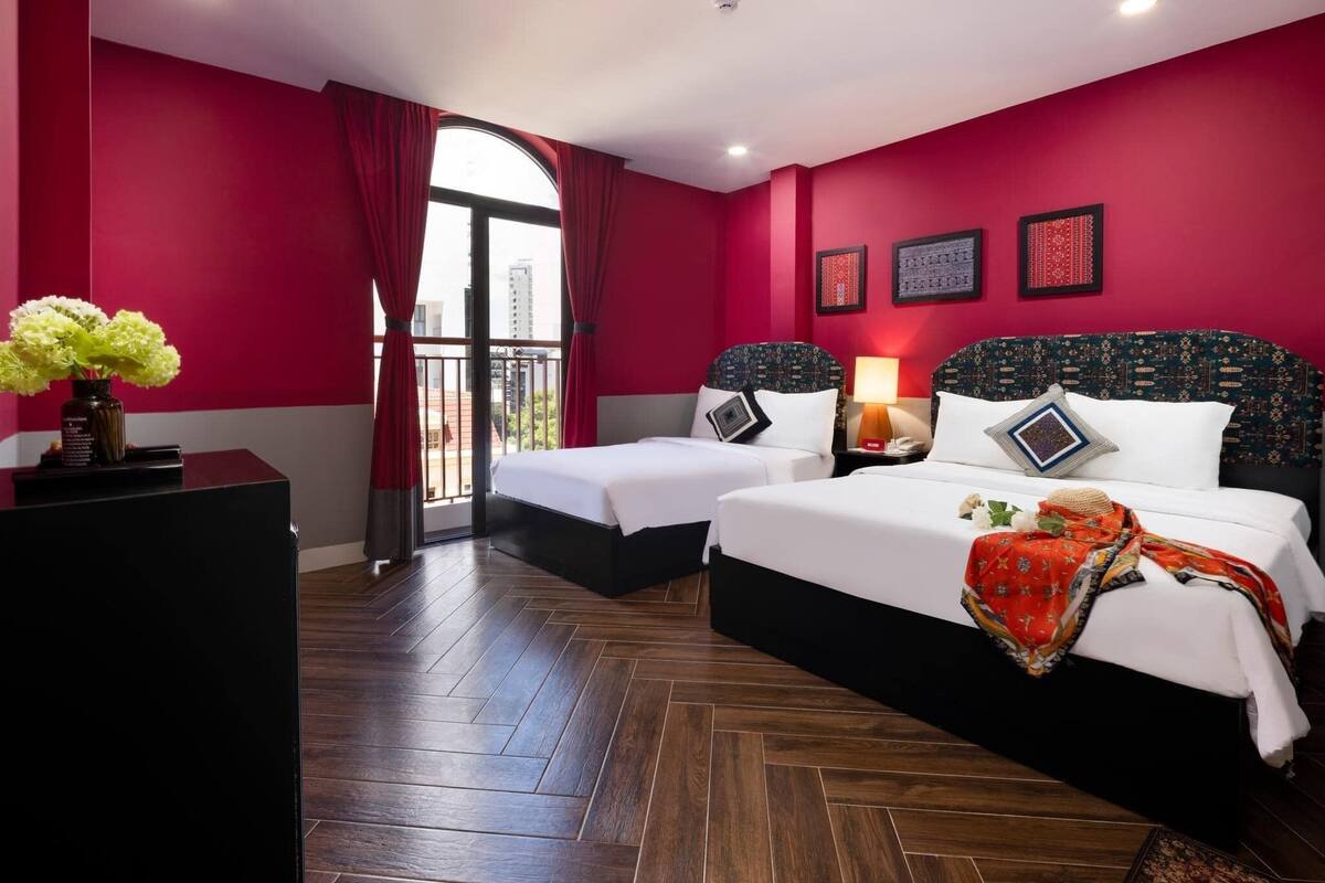 Habitación de hotel con dos camas, un ventanal con vistas y una pared roja.