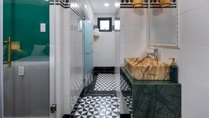 Une salle de bain moderne avec un carrelage au motif géométrique, un lavabo en marbre et une douche à parois de verre.