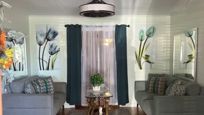 Una sala de estar con dos sofás, una mesa de centro, un espejo decorativo y obras de arte en las paredes.