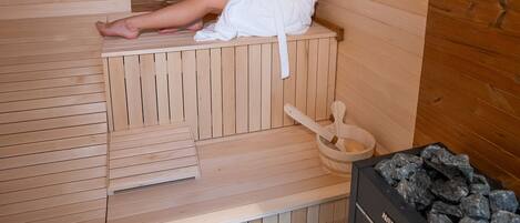 Una sala de sauna con bancos de madera y un calentador de sauna.