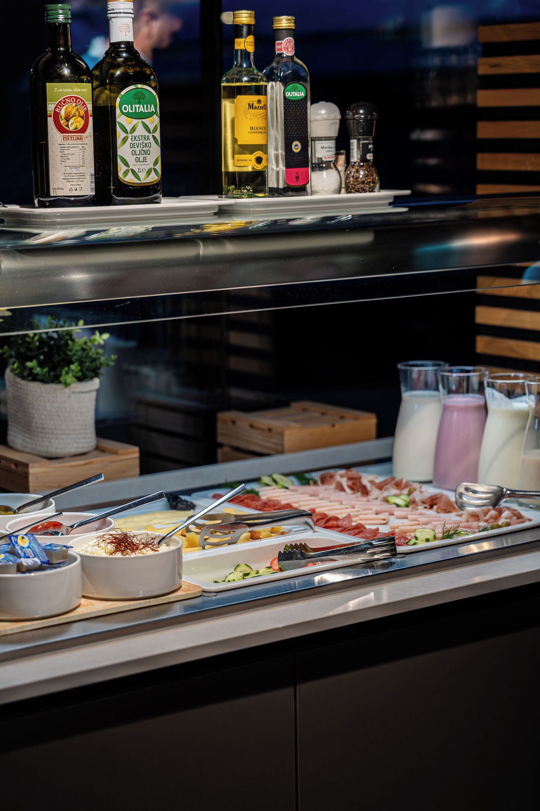 Un buffet proposant une variété de plats et d’accompagnements, notamment des bouteilles d’huile d’olive et de lait.