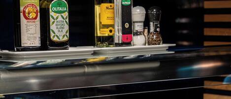 Un buffet proposant une variété de plats et d’accompagnements, notamment des bouteilles d’huile d’olive et de lait.