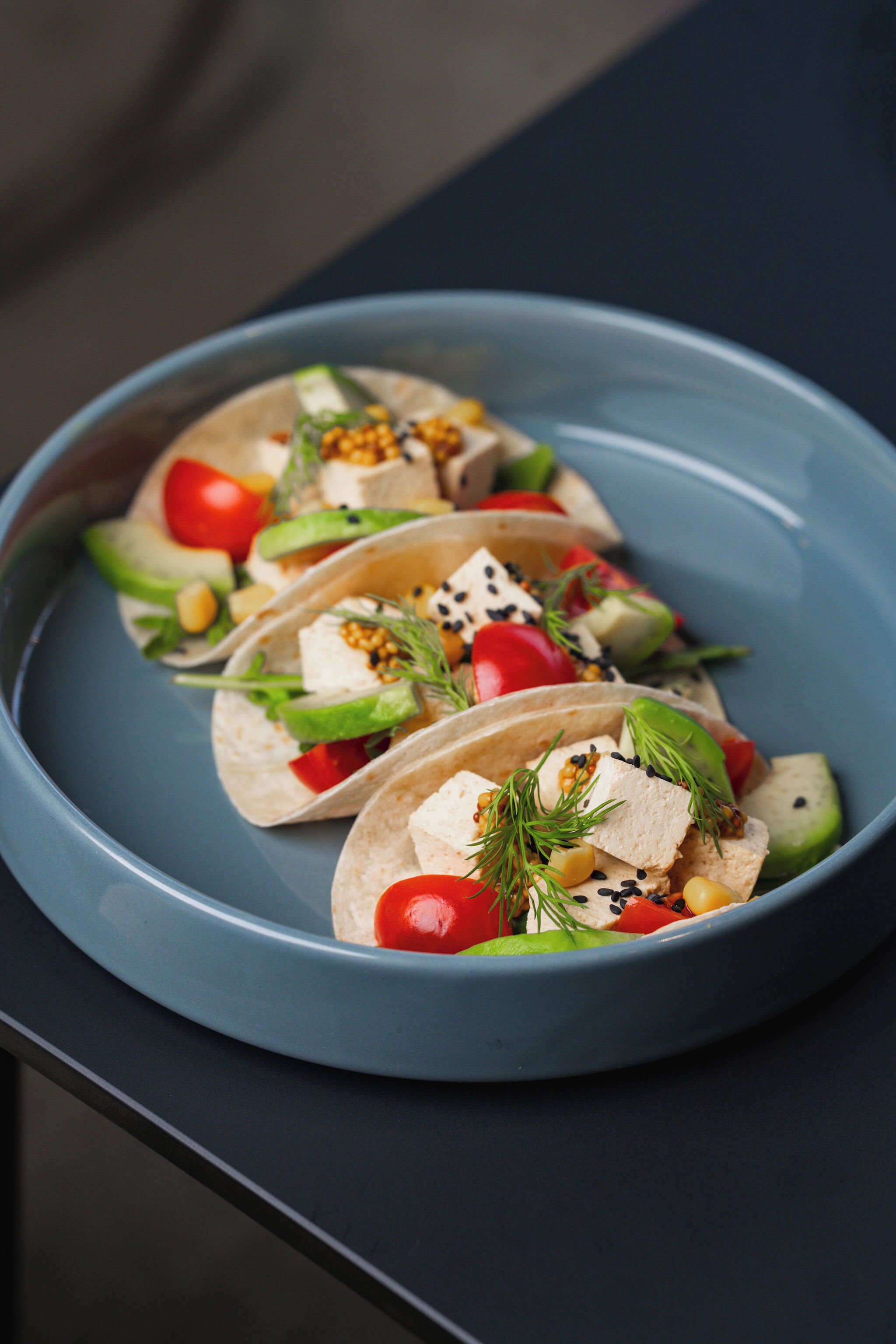 Three tacos on a blue plate.