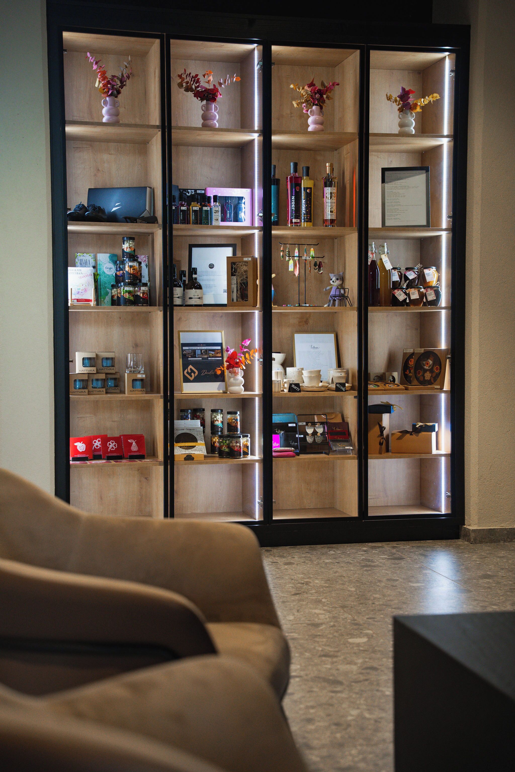 Ein Zimmer mit einem großen, hölzernen Bücherregal voller verschiedener Gegenstände, einem braunen Sofa und einem Fliesenboden.