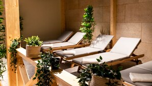 A spa area with wooden loungers, potted plants, and a stone wall. - Hotel Lonca (Skofja Loka)
