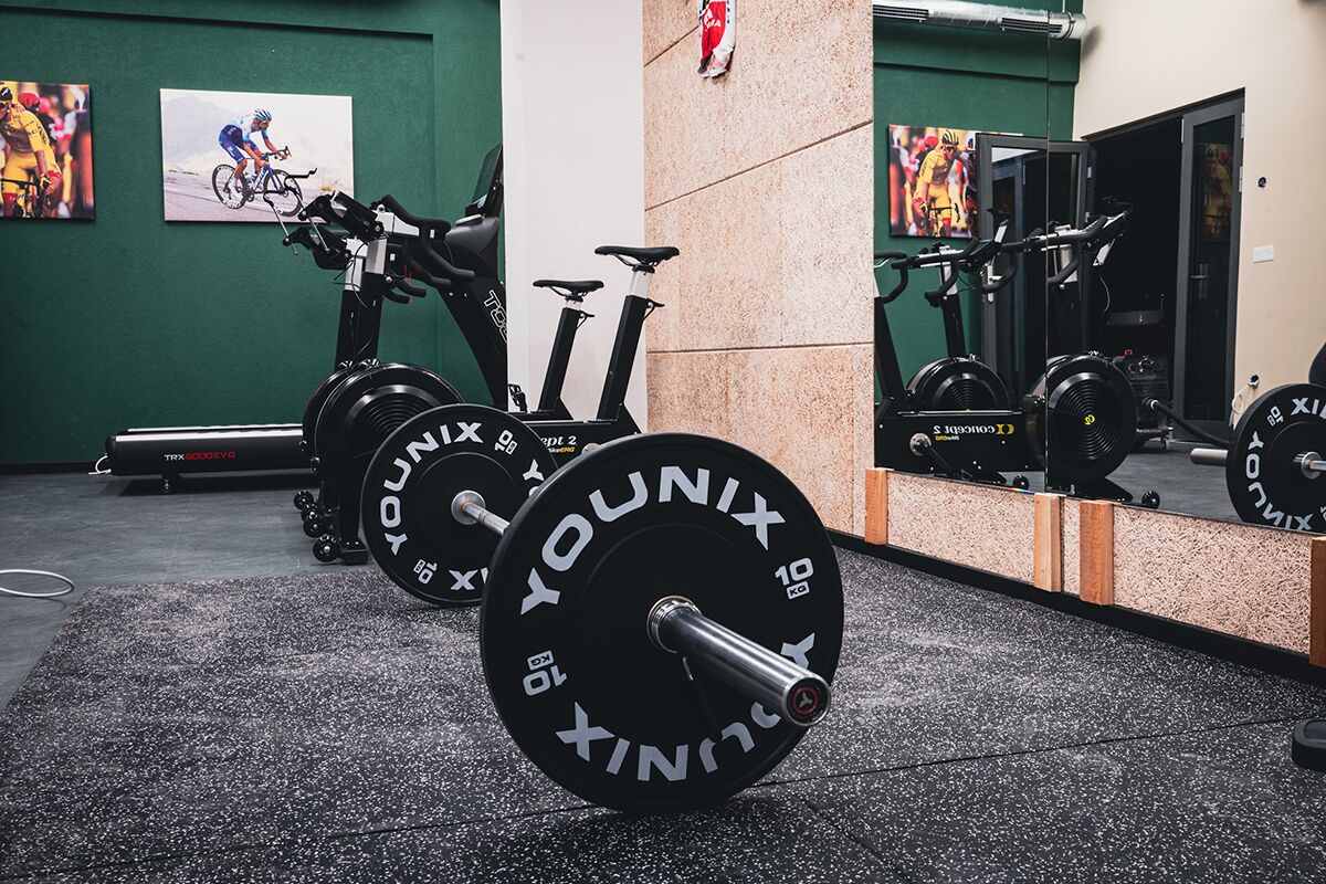 A gym with weightlifting equipment, exercise bikes, and a mirror reflecting the equipment.