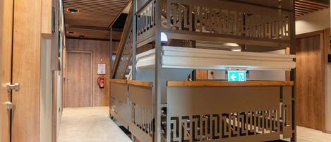 Una habitación de hotel con suelo de madera, una cama con cabecera y una separador de madera con diseño geométrico.