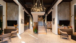 A spacious lobby with a central staircase, modern lighting, and seating areas. - Hotel Lonca (Skofja Loka)
