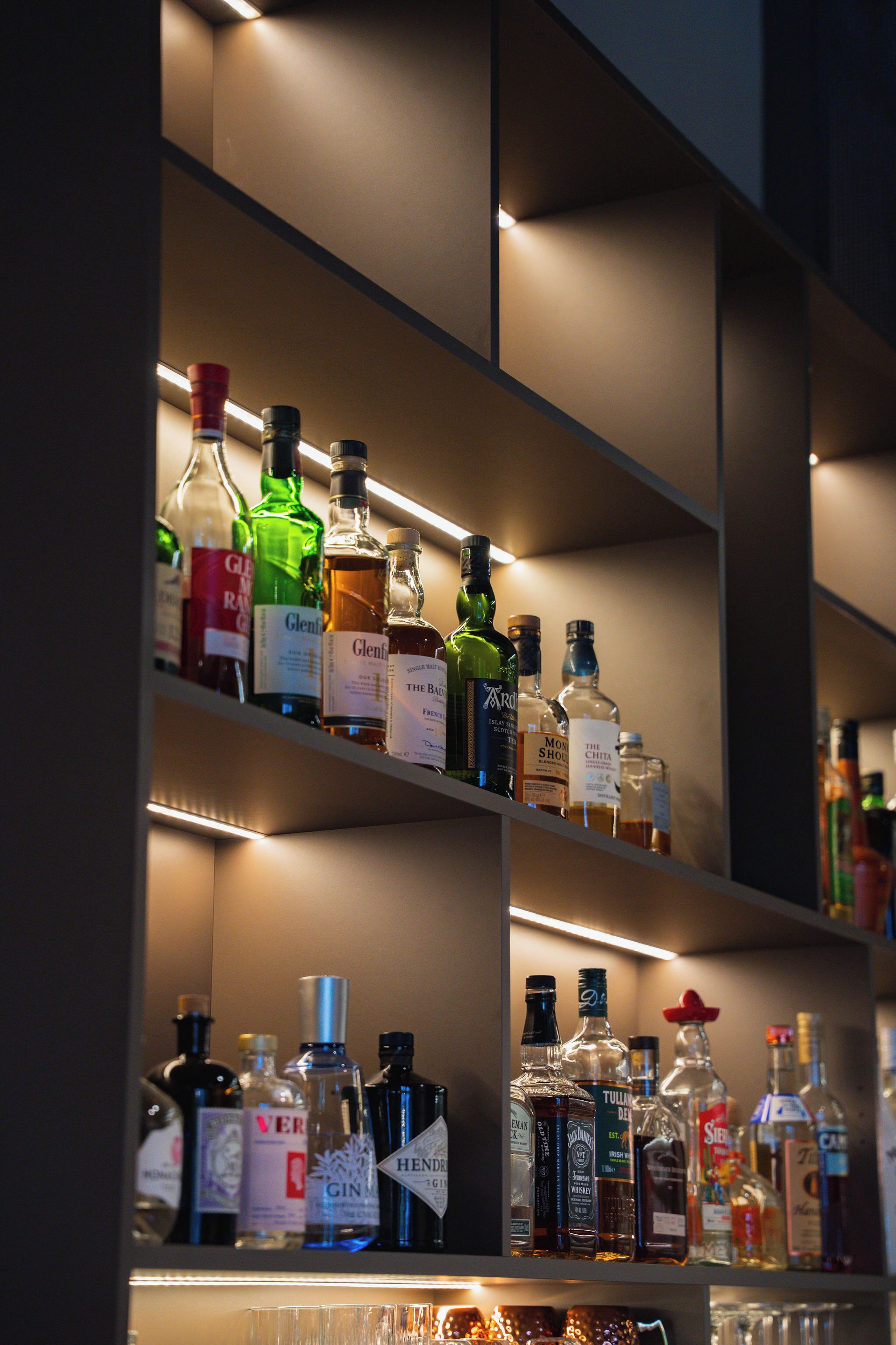 Un bar bien éclairé, contenant différentes bouteilles d’alcool.