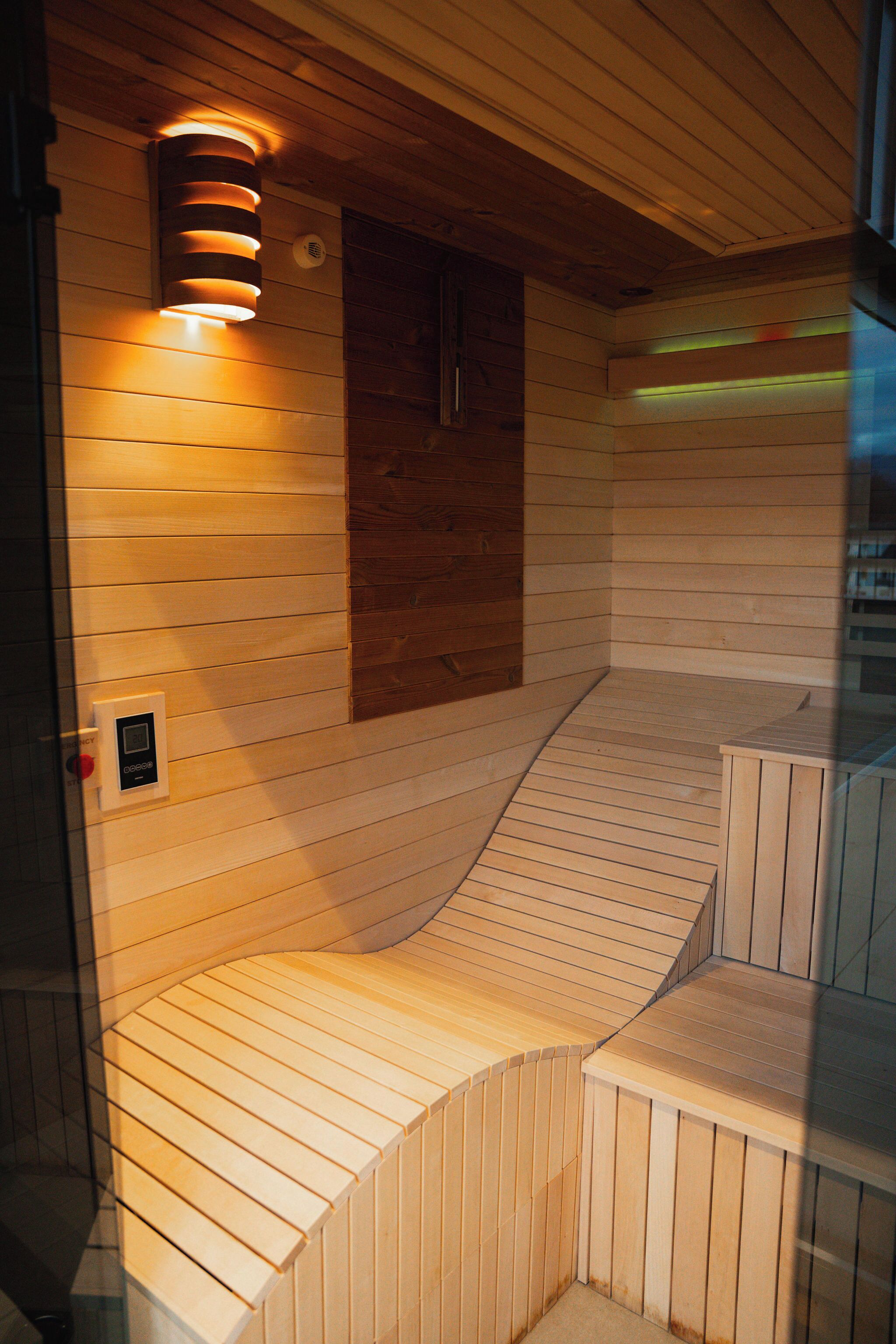 A sauna with wooden benches and a control panel.