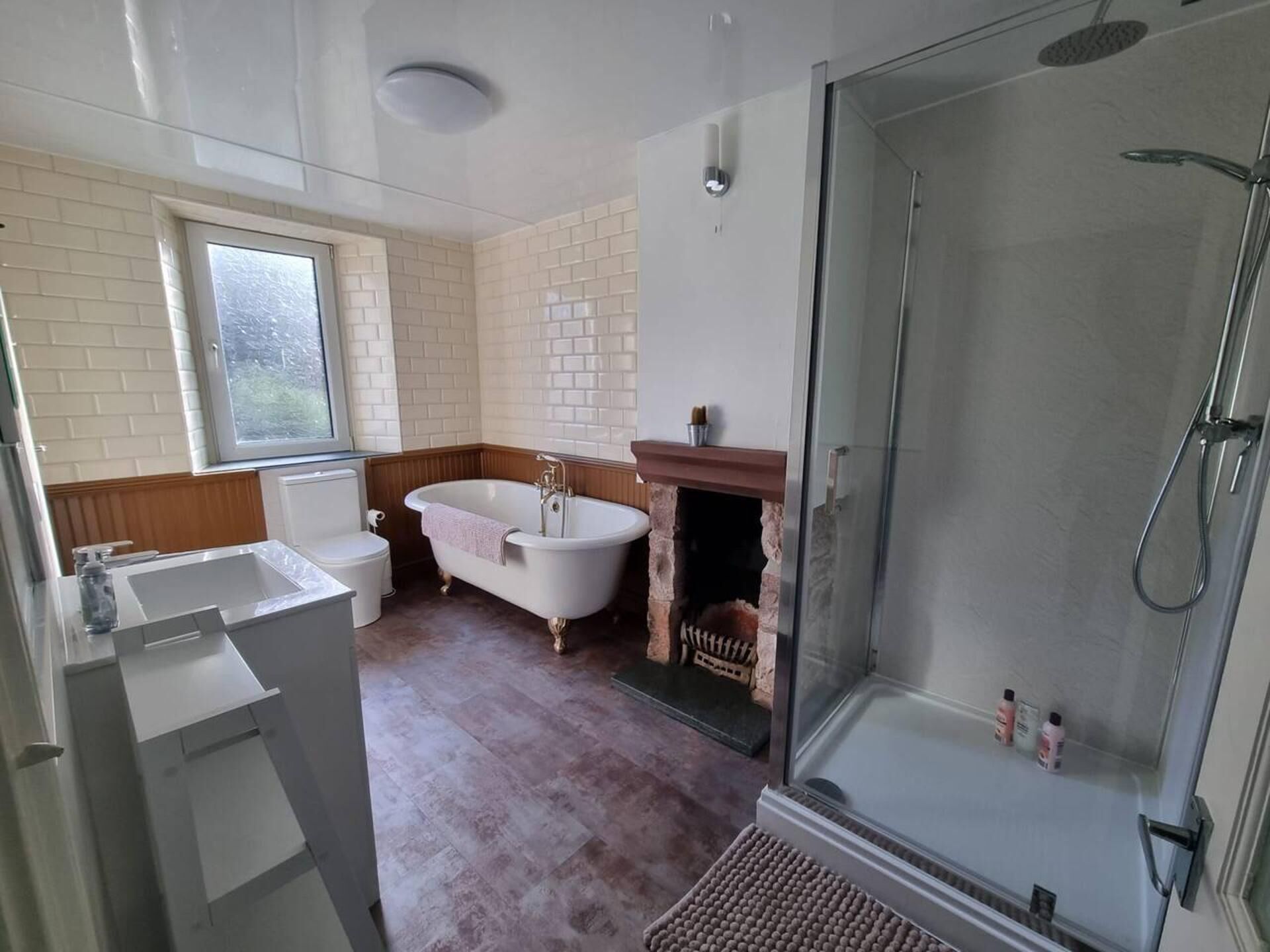 A bathroom with a bathtub, a glass-enclosed shower, a toilet, and a sink.