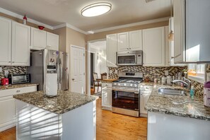 A modern kitchen with white cabinetry, a stainless steel refrigerator, a microwave, a stove, and a built-in oven.