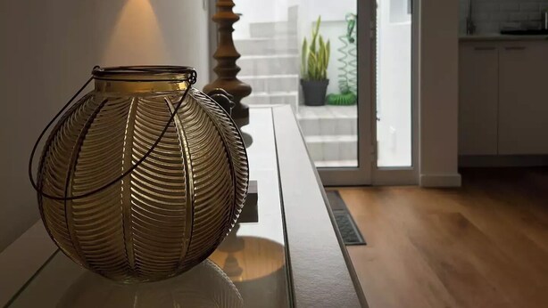 Une cuisine moderne avec un coin repas, agrémentée d’une lampe et d’un vase décoratif posés sur une table.