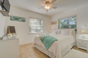 A bedroom with a bed, a nightstand, a ceiling fan, and a window with blinds.