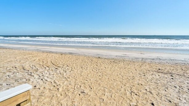 A sandy beach with a wooden structure in the foreground. - Surfside Beach House (St. Augustine)