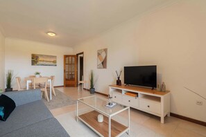 Un salon moderne comprenant un canapé, une table basse, un téléviseur et un coin repas avec des chaises et une table.