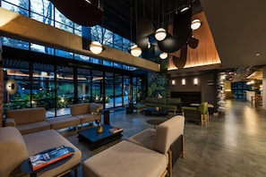 Eine großzügige Lobby mit Sitzbereichen, großen Fenstern und moderner Beleuchtung.