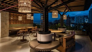An outdoor seating area with round tables and cushioned benches, surrounded by tall, woven light fixtures. - Faranda Collection Medellin, a Member of Radisson Individuals (Medellín)