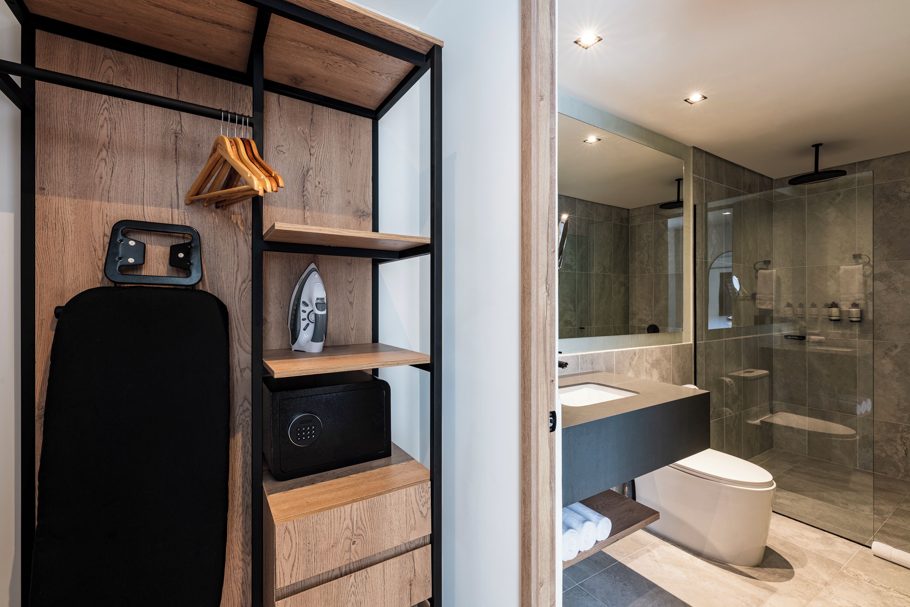 A modern bathroom with a wooden vanity, a black chair, a radio, and a glass shower enclosure.