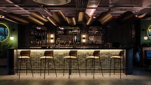 A bar area with a counter, bar stools, and shelves of bottles. - Faranda Collection Medellin, a Member of Radisson Individuals (Medellín)
