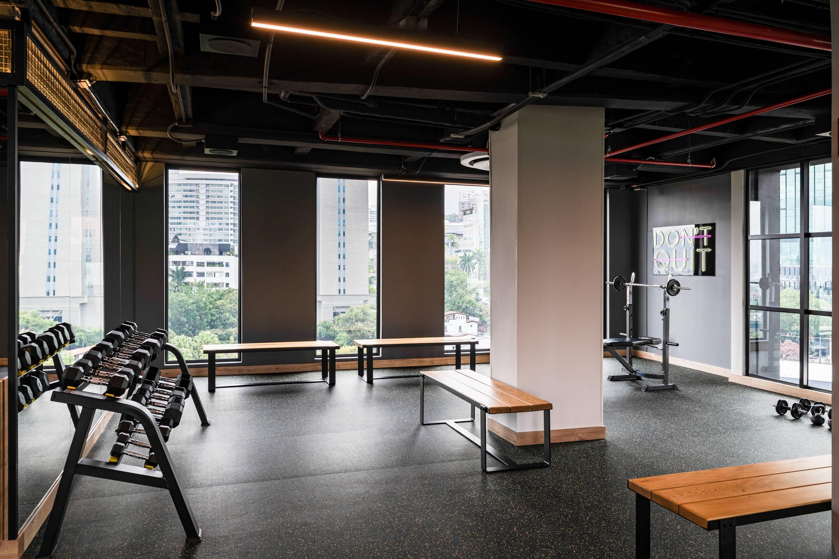 Une salle de sport équipée de bancs, d’haltères et d’une affiche motivante.