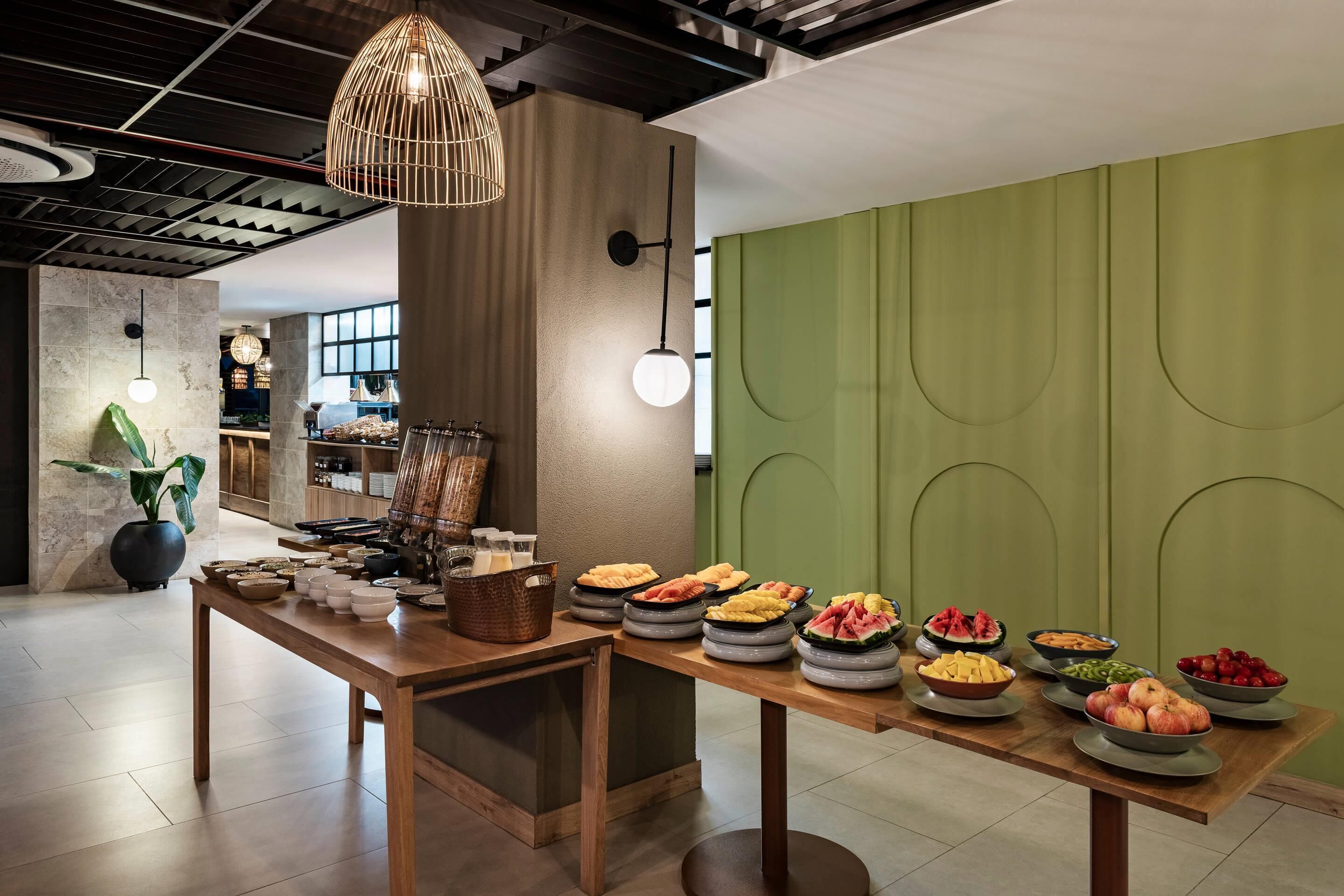 Une table de buffet proposant une variété de plats, ainsi qu’un intérieur moderne avec des poutres apparentes et des murs verts.