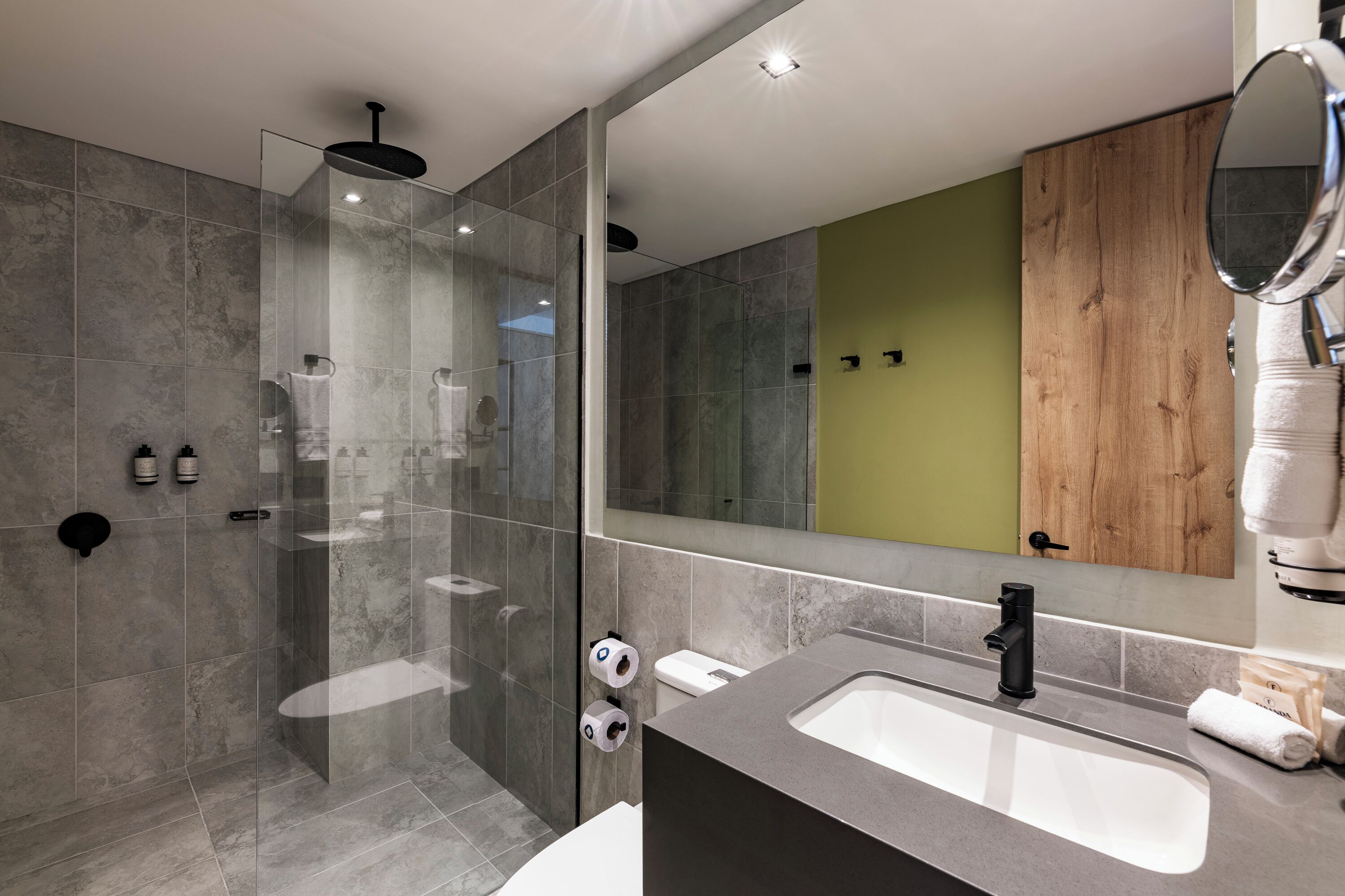 A modern bathroom with a glass shower enclosure, a large mirror, and a sink with a faucet.