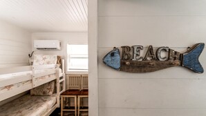 Una habitación con literas, un letrero con forma de pez de madera y una ventana.