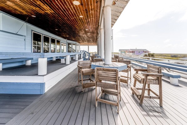 A wooden deck with benches and tables, overlooking a coastal area.