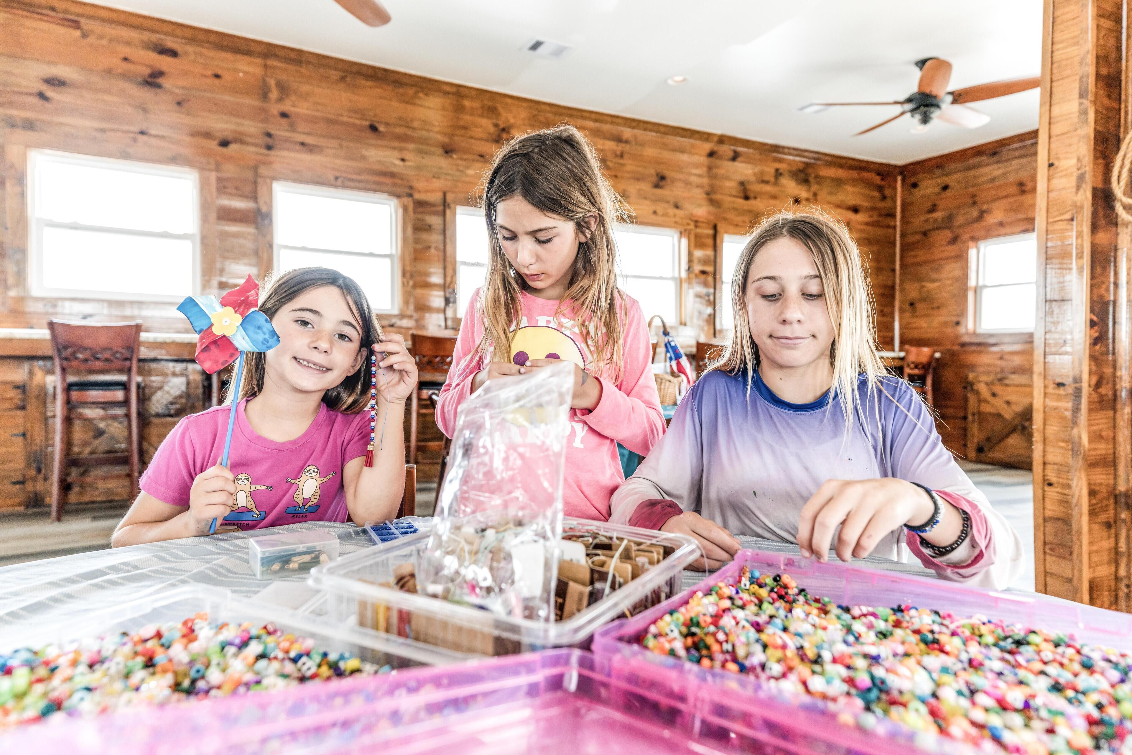 A wooden interior with a table filled with colorful beads and a plastic container.