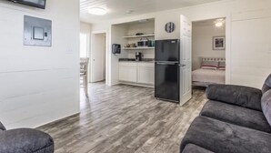 A compact living space with a kitchenette, a dining area, and a bedroom. - The Pelican - Pelican - Two Bedroom Cottage (Freeport)