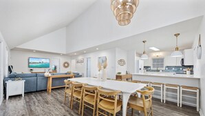 A modern kitchen with white cabinets, a wooden dining table, and a bar area. - 2 blocks 2 beach, Golf Cart, Outdoor Bar, Dogs Welcome, Beach Gear (Atlantic Beach)
