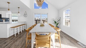 A spacious kitchen with a long dining table, wooden chairs, and a hanging light fixture. - 2 blocks 2 beach, Golf Cart, Outdoor Bar, Dogs Welcome, Beach Gear (Atlantic Beach)