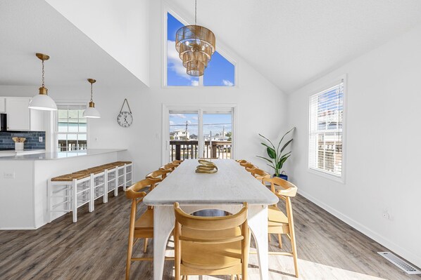 A spacious kitchen with a long dining table, wooden chairs, and a hanging light fixture. - 2 blocks 2 beach, Golf Cart, Outdoor Bar, Dogs Welcome, Beach Gear (Atlantic Beach)