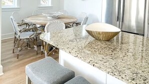 A modern kitchen with a central island, stainless steel appliances, and a hanging light fixture. - Moonlight and Starlight Escape (Panama City Beach)