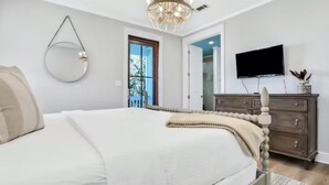 A bedroom with a bed, a dresser, a TV, and a chandelier. - Moonlight and Starlight Escape (Panama City Beach)
