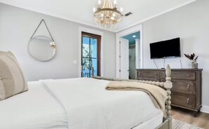 A bedroom with a bed, a dresser, a TV, and a chandelier. - Moonlight and Starlight Escape (Panama City Beach)