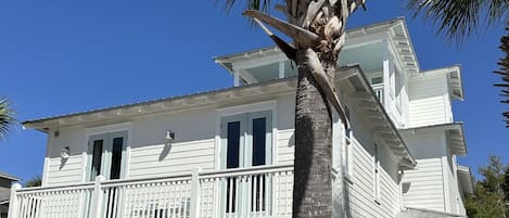 A two-story white house with a balcony, garage, and a palm tree in the foreground.