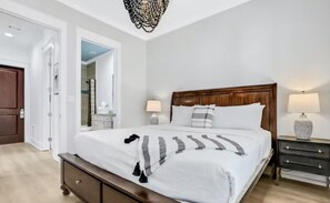 Une chambre à coucher avec un grand lit, des tables de chevet, une tête de lit en bois et un lustre.