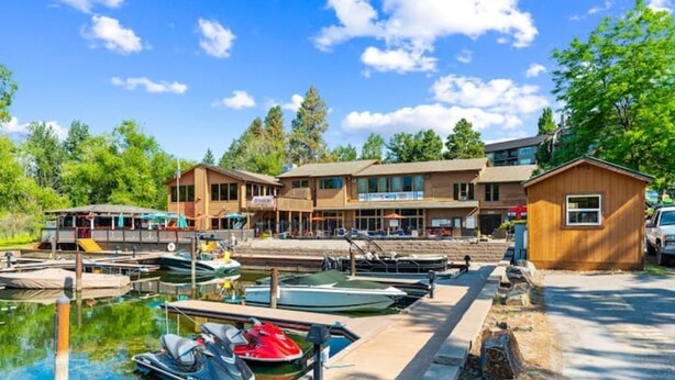 Un puerto deportivo con barcos amarrados, una cabaña de madera y un edificio con varias ventanas y un letrero.