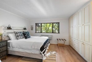 A bedroom with a bed, a nightstand, a window, and a wardrobe.