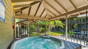 Un jacuzzi bajo una pérgola de madera con vista a un patio trasero.