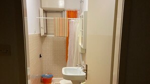 Ein kleines Badezimmer mit Toilette, Waschbecken und Duschbereich.