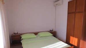 Ein Zimmer mit einem Einzelbett, einem Holzkopfstück, einem Nachttisch mit Lampe und einem Kleiderschrank.