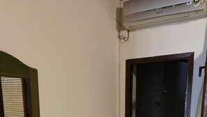 Ein Zimmer mit Fernseher auf einem Tisch, einer Steckdose und einer Tür zu einem anderen Raum.